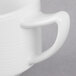 A close-up of a white porcelain stacking cup with a handle.