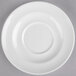 A white porcelain saucer with a rim on a gray surface.