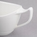 A close-up of a white porcelain sauce boat with a handle.