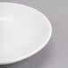 A close-up of a white Reserve by Libbey round porcelain dipping dish with a white rim.