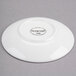 A white porcelain round dipping dish with a small black logo.