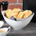 A white porcelain bowl filled with pieces of bread on a table.