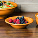 A Fiesta Tangerine china bowl filled with blueberries and raspberries.