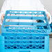 A chef holding a blue Carlisle OptiClean glass rack extender over a blue plastic tray.