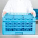 A chef holding a blue Carlisle OptiClean glass rack extender with holes.