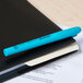 A Universal blue chisel tip highlighter pen clipped to a black notebook.