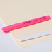 A Universal fluorescent pink highlighter pen with a pocket clip sitting on a white envelope.