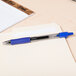A Pilot G2 pen with blue liquid in it rests on a notebook.