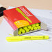 A Universal fluorescent yellow chisel tip pen style highlighter resting on a box of yellow highlighters.