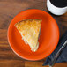 An orange Fiesta® appetizer plate with a slice of pie next to a mug of coffee.