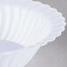 A close-up of a white Fineline Flairware bowl with scalloped edges.