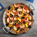 A large American Metalcraft stainless steel paella pan with rice, shrimp, and mussels.