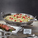 An American Metalcraft stainless steel paella pan filled with food on a table.