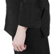 A person wearing a Mercer Culinary black long sleeve chef jacket.