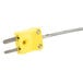 A yellow electrical plug with two metal tips.