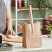 A woman using a brown paper bag to make pizza dough.