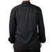 A man wearing a Mercer Culinary black long sleeve chef jacket with black buttons.