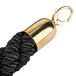 A close up of a black braided rope with gold ends.