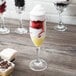 A close up of a GET SAN plastic champagne flute with fruit and whipped cream.
