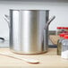 A large silver Vollrath stock pot on a wooden surface.