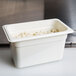 A white Cambro 1/4 size plastic food pan with food inside.