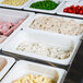 A row of Cambro white plastic food pans filled with food on a counter.