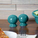 A table with a bowl of salad and a Turquoise Fiesta salt and pepper shaker set.