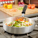 A Vollrath Wear-Ever saute pan filled with vegetables on a stove.