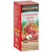 A box of Bigelow Cinnamon Apple Herbal Tea Bags on a table with a basket of apples.