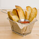 A basket of potato wedges with red sauce.