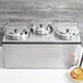 A Vollrath stainless steel countertop food warmer with three bowls of soup.