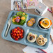 A Carlisle slate blue 6 compartment tray with food on it, including a bowl of tomatoes and a bowl of fruit.