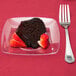 A Fineline clear plastic dessert plate with chocolate cake and strawberries on it.