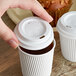 A hand holding a Choice white plastic cup of coffee with a white paper lid.