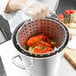 A person holding a Vollrath Wear-Ever 32 qt. Boiler/Fryer Set with lobsters inside.