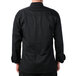 A man wearing a Mercer Culinary black long sleeve chef jacket with cloth knot buttons.