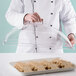 A person holding a Cambro clear dome display cover over a tray of cookies.