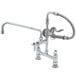 A T&S chrome deck mounted pre-rinse faucet with a hose and sprayer.