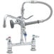 A T&S chrome deck mounted pre-rinse faucet with two handles and a hose.