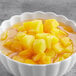 A white bowl of diced yellow peaches.