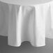 A white 132" round Intedge tablecloth with a hemmed edge on a table.