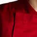 A close up of a Chef Revival tomato red chef jacket with hidden snap buttons.