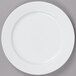 A white Arcoroc porcelain salad plate with a white rim on a gray surface.