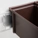 A brown plastic box with a metal frame holding six brown plastic bins on a metal wall mounting rail.