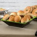 A tray of food in green and black square melamine bowls on a table.