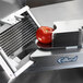 An Edlund tomato slicer cutting a tomato on a table.