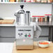 A Robot Coupe CL50 Ultra food processor on a counter with a bowl of shredded carrots.