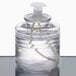 A clear glass container with a white lid containing Sterno Soft Light Clear Liquid Candle Fuel.