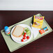 A Cambro Key Lime dietary tray with a sandwich, chips, and a drink on it.