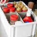 A Short Metro gray plastic tote box divider with condiments in it.